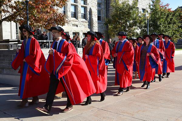 Queen's University graduates in convocation gowns walking in lines of two