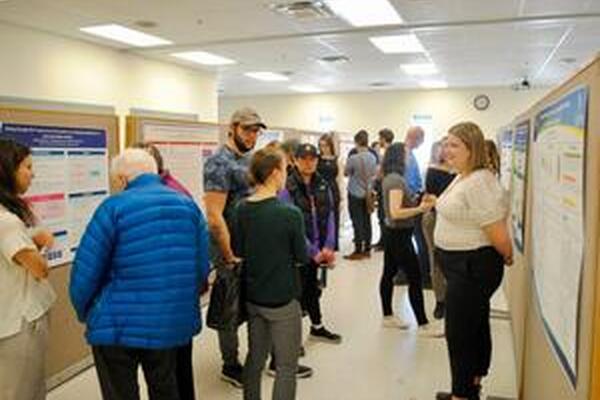 small groups of people in conversation in front of research posters