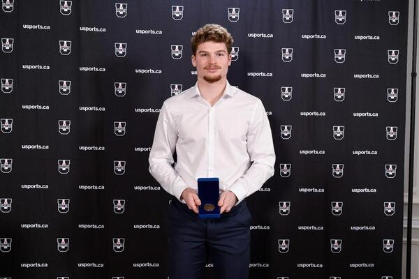 Photograph of Ashton Miller Melancon holding award at USPORTS ceremony.