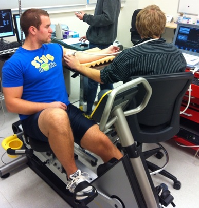 A man on an exercise machine sitting next to a researcher