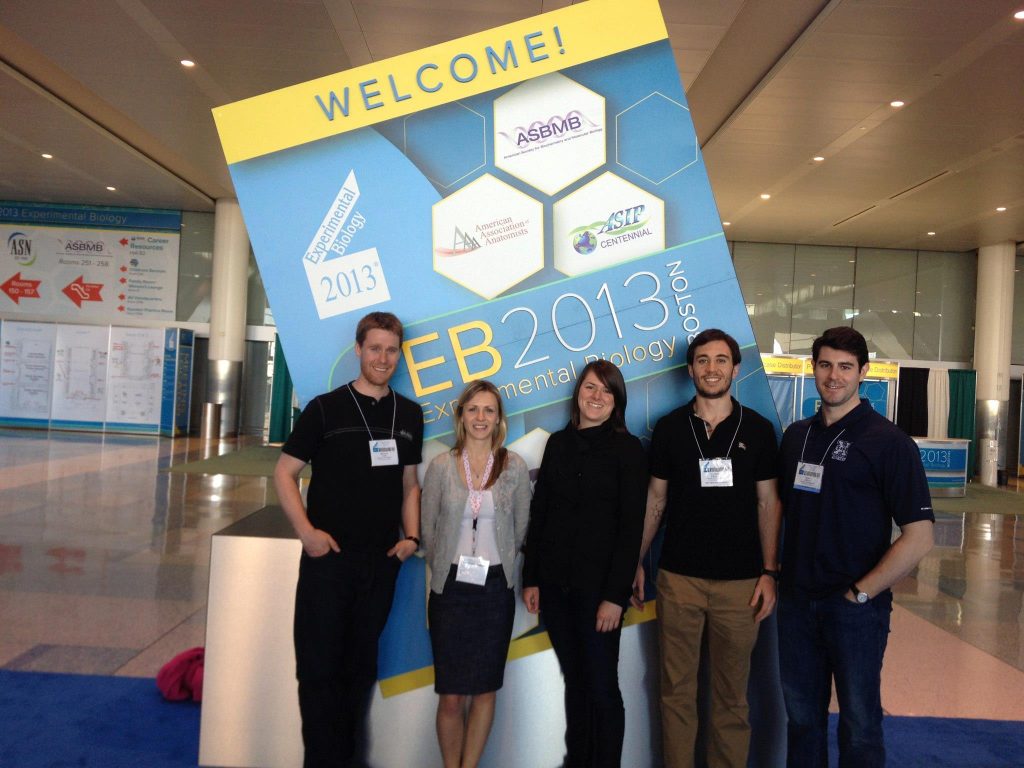 A group of people standing in front of an Experimental Biology poster at a conference